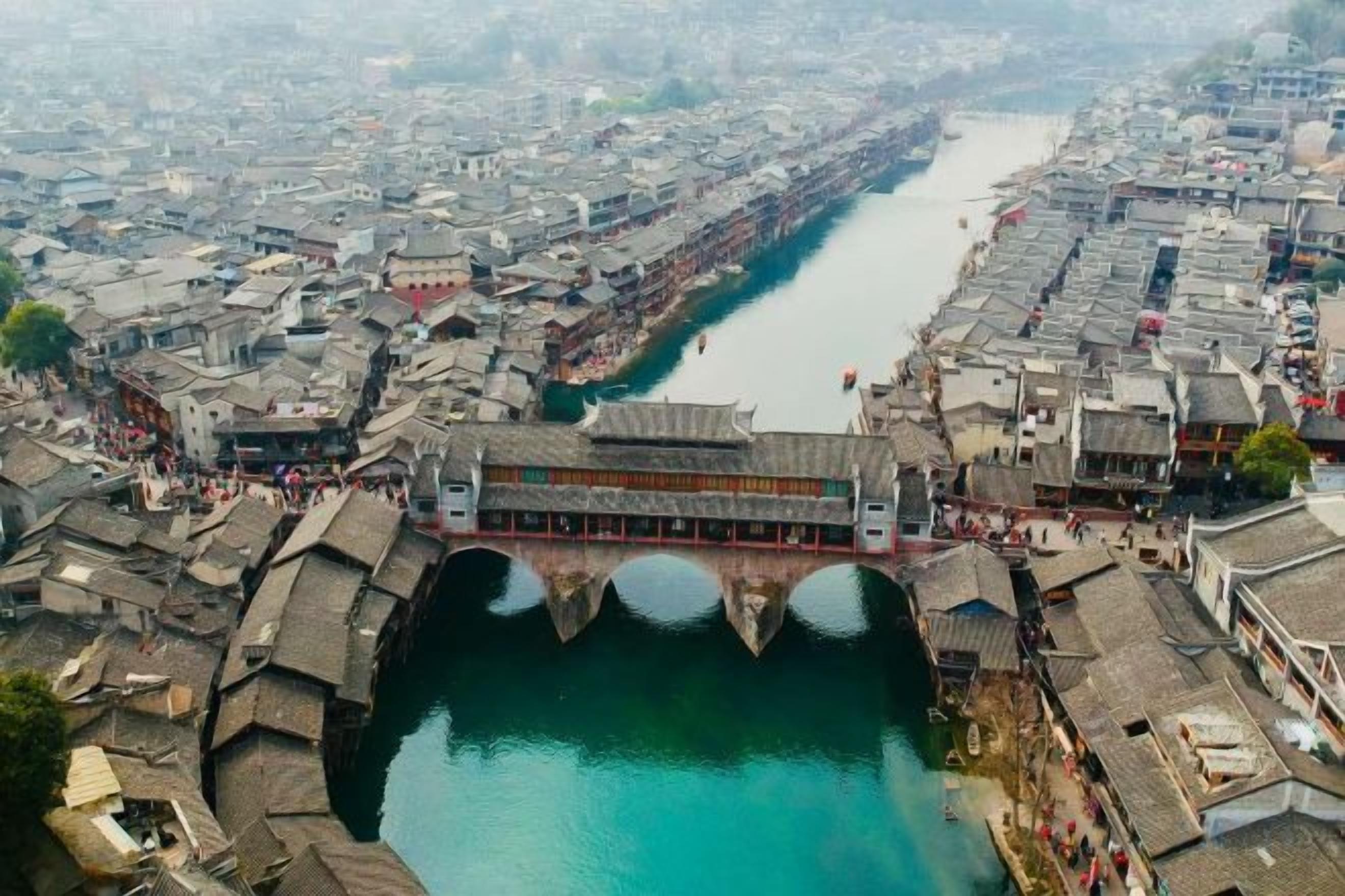 Une rivière traverse une ville historique, où l’on trouve des bâtiments traditionnels et un pont.