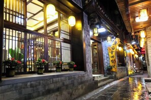 A traditional building with a tiled entrance, illuminated windows, and a sign with Chinese characters.