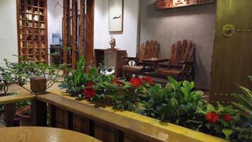 A room with a wooden table, chairs, a bookshelf, and potted plants.