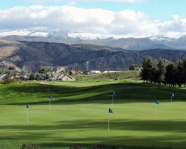 Un campo de golf con vistas despejadas a las montañas circundantes y una zona residencial al fondo.