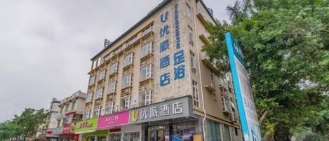 A multi-story building with commercial establishments on the ground floor, including a pharmacy and a store with a prominent sign.