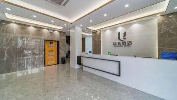 A hotel reception area with a marble floor, a reception desk, and a wall-mounted sign.