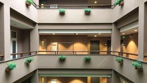 Un intérieur à plusieurs niveaux, doté d’un escalier central, de rampes et de plantes en pot.
