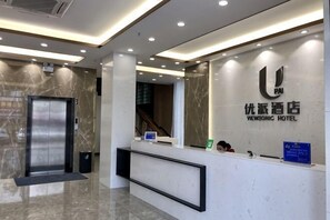 A reception desk with a digital screen, a reception area, and a wall-mounted sign with hotel branding. - Youpai Hotel (Zhongshan Hot Spring Sanxiang Branch) (Zhongshan)
