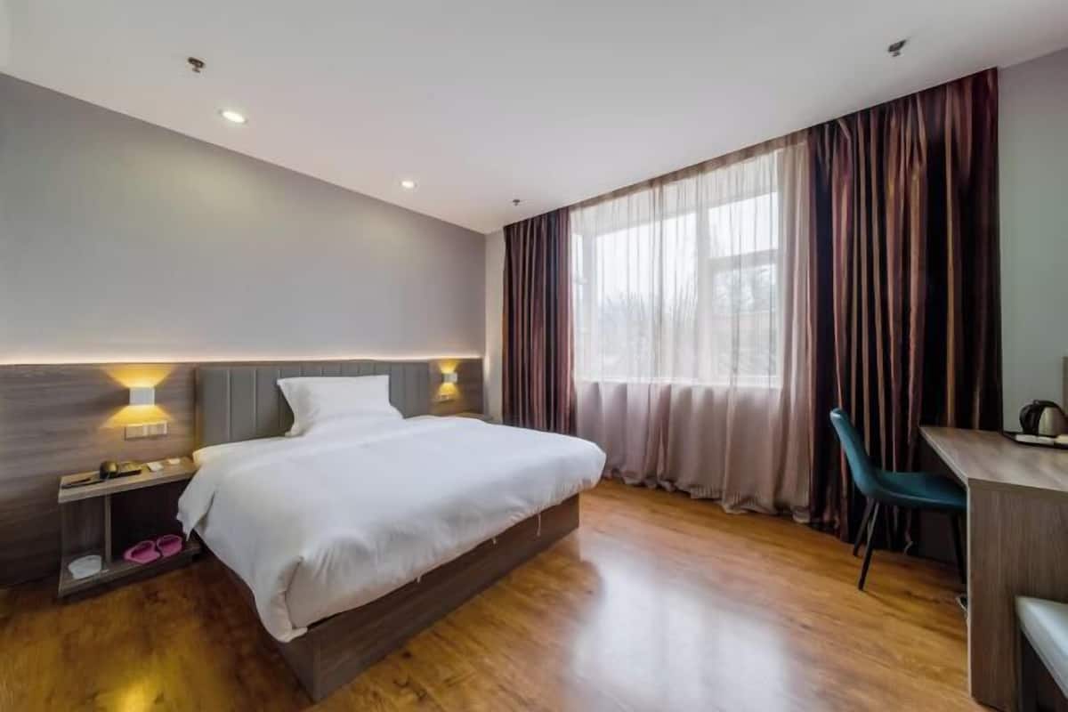 Quarto de hotel moderno com uma cama grande, luminárias de cabeceira, uma escrivaninha e vista para o exterior.