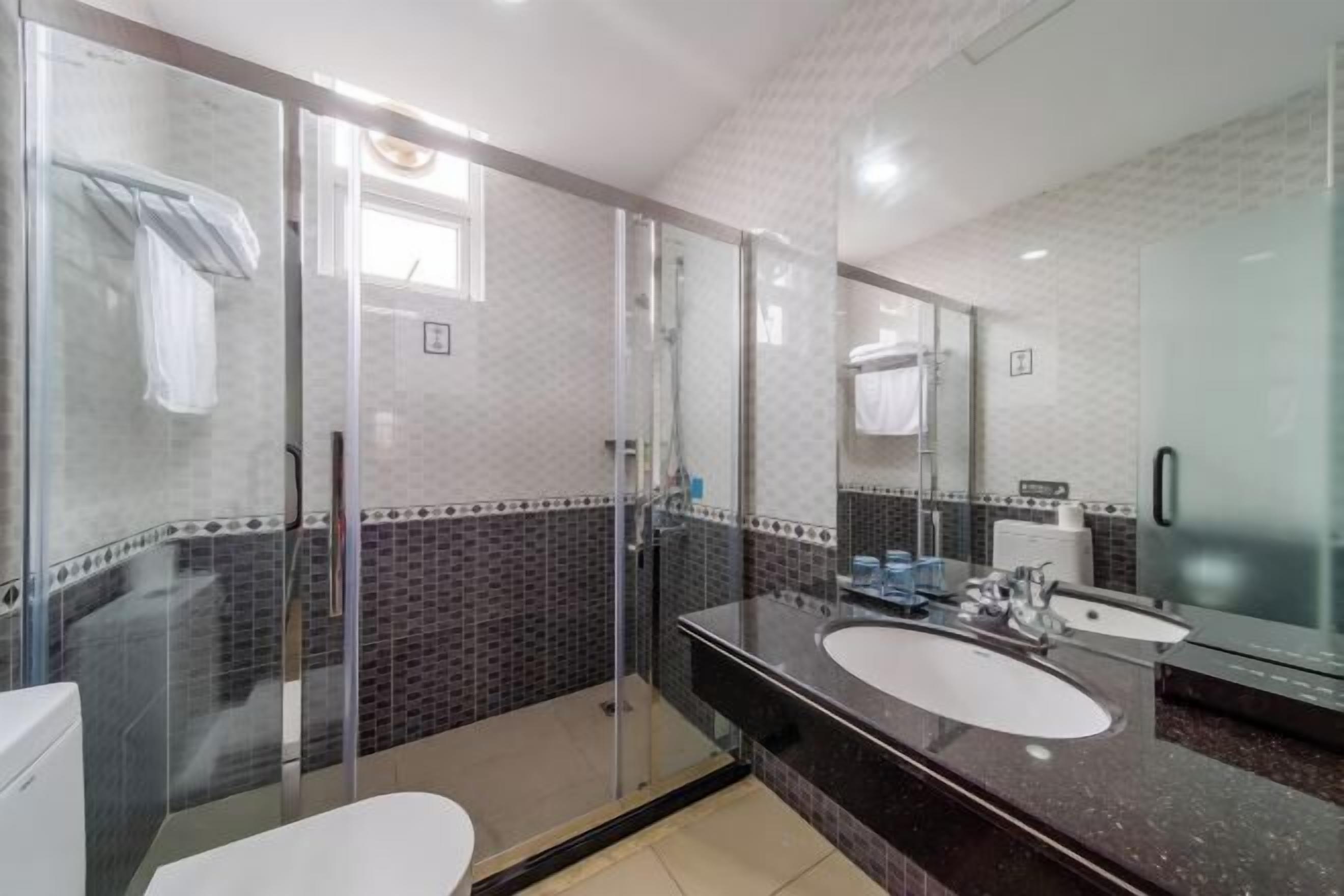 A modern bathroom with a glass shower enclosure, a double sink vanity, and a large mirror.