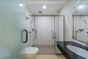 A modern bathroom with a glass shower enclosure, a white toilet, and a black sink with a large mirror. - Youpai Hotel (Zhongshan Hot Spring Sanxiang Branch) (Zhongshan)