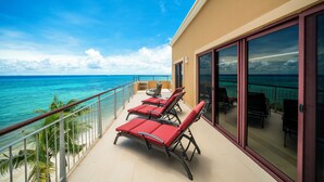 Ein Balkon mit roten Liegestühlen mit Blick auf den Ozean.