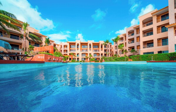 Un hôtel doté d’une piscine, de plusieurs balcons et de palmiers.