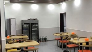 A modern dining area with multiple tables and chairs, a refrigerator, and a kitchen area with utensils. - Lanyu Inn (Yichang Three Gorges Dam) (Yichang)