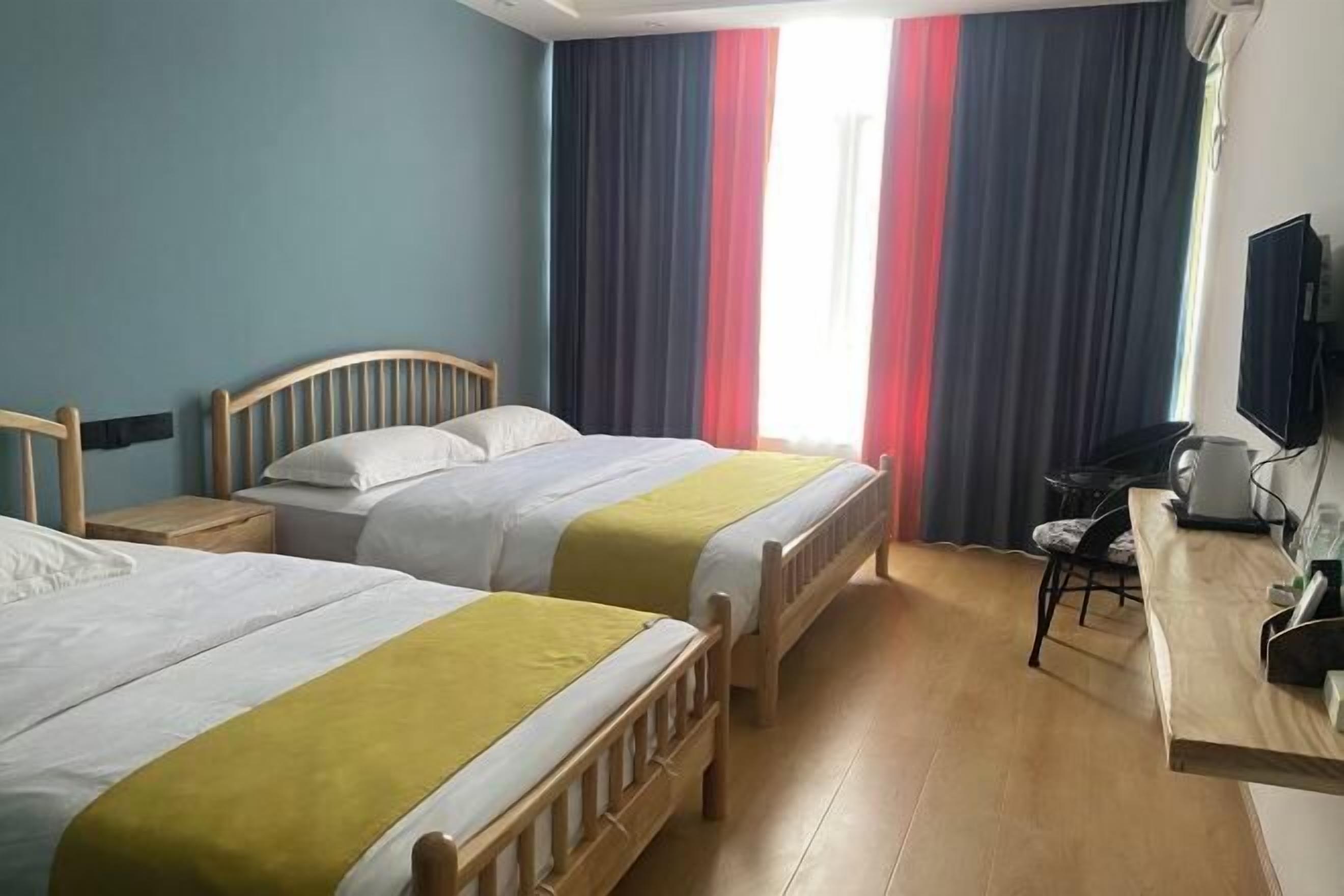 A hotel room with two beds, a desk, a chair, and a television on the wall.