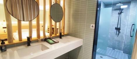 Un baño con un lavamanos blanco, dos espejos, una ducha y baldosas de suelo con diseño.