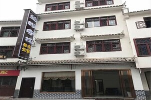 Un edificio tradicional con varios pisos, ventanas amplias y un letrero llamativo a la izquierda.