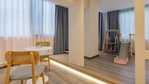 A hotel room with a dining table, two chairs, a high chair, and a large mirror. - Lanyu Inn (Yichang Three Gorges Dam) (Yichang)