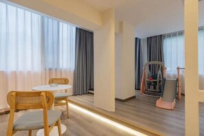 A hotel room with a dining table, two chairs, a high chair, and a large mirror. - Lanyu Inn (Yichang Three Gorges Dam) (Yichang)