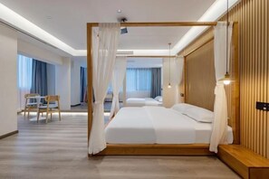 A modern hotel room with a large bed, a wooden headboard, and a separate seating area with a table and chairs.