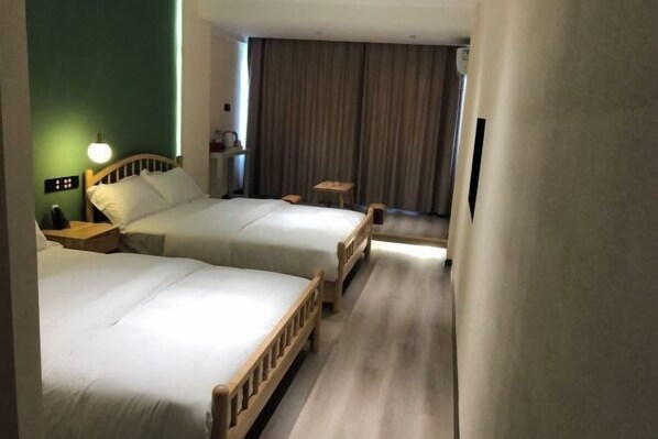 A hotel room with two beds, a small table, a chair, and a curtain.