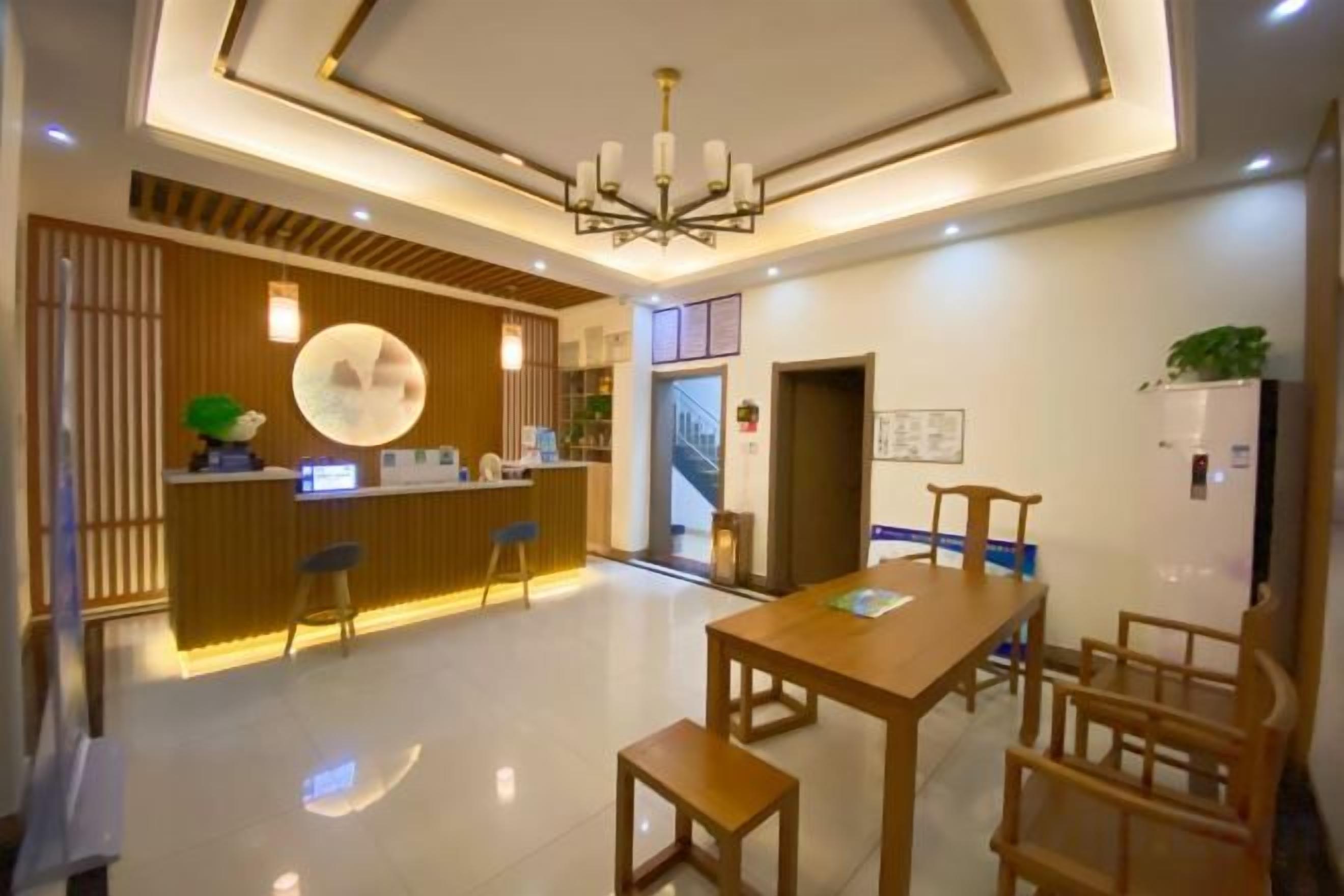 Un vestíbulo de hotel con una recepción, una zona de estar y una escalera.