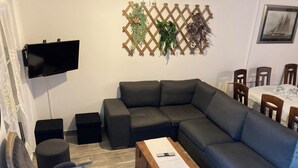 Ein modernes Wohnzimmer mit Ecksofa, Couchtisch, Wandfernseher und einer dekorativen Pflanzenwand.
