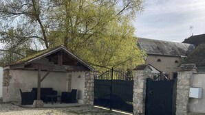 Ein Patio mit einem runden Tisch und vier Stühlen, umgeben von Steinmauern und einem Kiesweg.