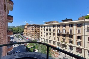 A multi-story building with balconies, a street view, and a clear sky.