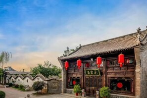A traditional building with a tiled roof, wooden doors, and red lanterns. - Yongyichang Inn (Pingyao County)