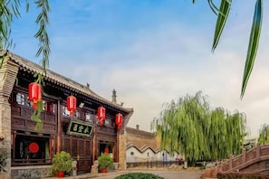 A traditional building with a sign, wooden architecture, and a weeping willow tree.