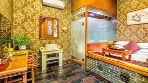 A room with patterned wallpaper, a wooden bench, a small table, a mirror, and a window. - Yongyichang Inn (Pingyao County)