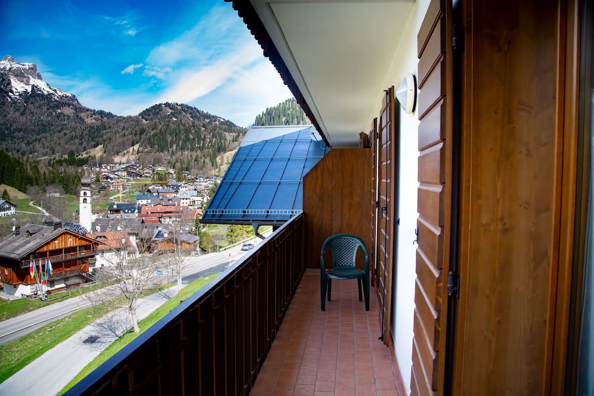 A balcony with a view of a town and mountains, a chair, and a wooden door.