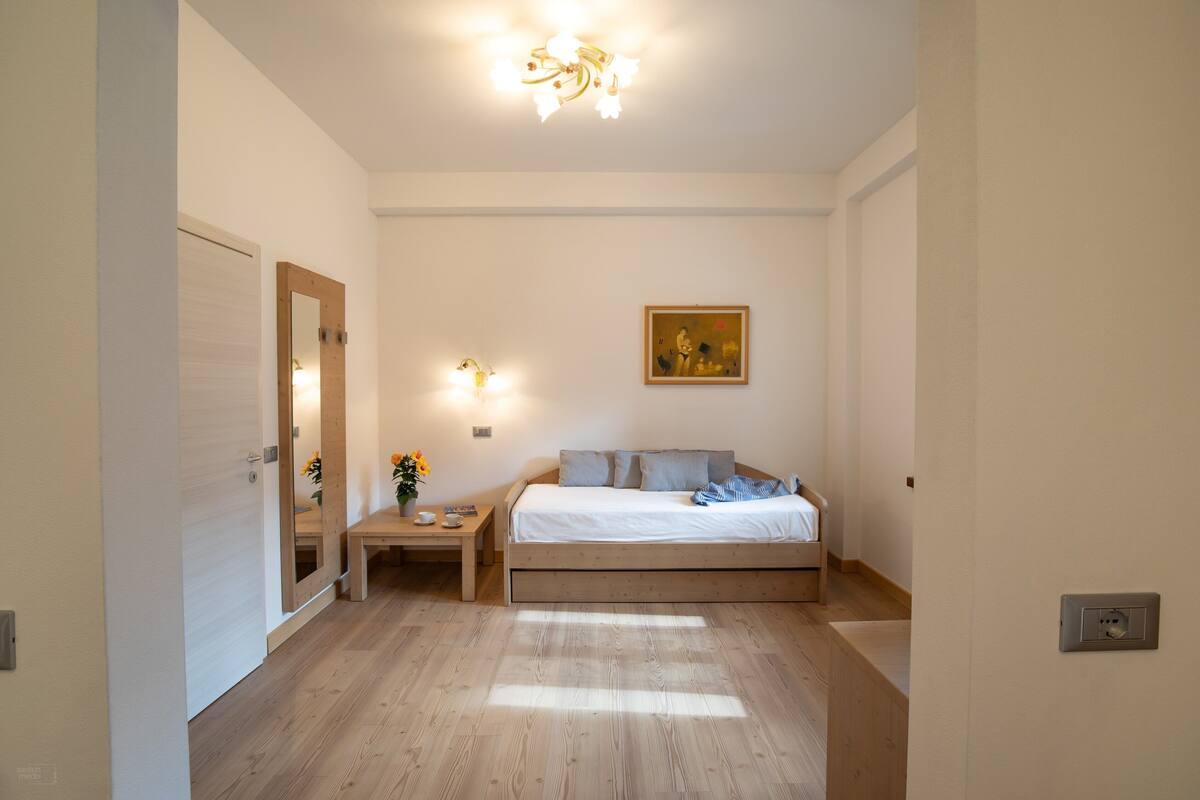 A bedroom with a bed, bedside table, and a painting on the wall.