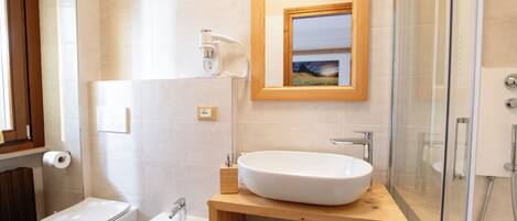 Un baño moderno con inodoro, bidé y un lavamanos grande con tocador de madera.