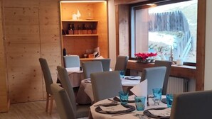 A dining area with a wooden interior, a window with a view, and a table set for four. - HOTEL MAE' (Val di Zoldo)