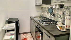 Una cucina moderna con piano cottura a gas, mobili in acciaio inossidabile e zanzariera decorata.