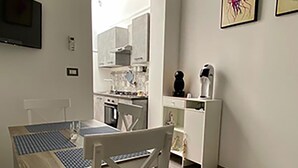 Un'area pranzo con tavolo e sedie, una cucina sullo sfondo e opere d'arte alle pareti.