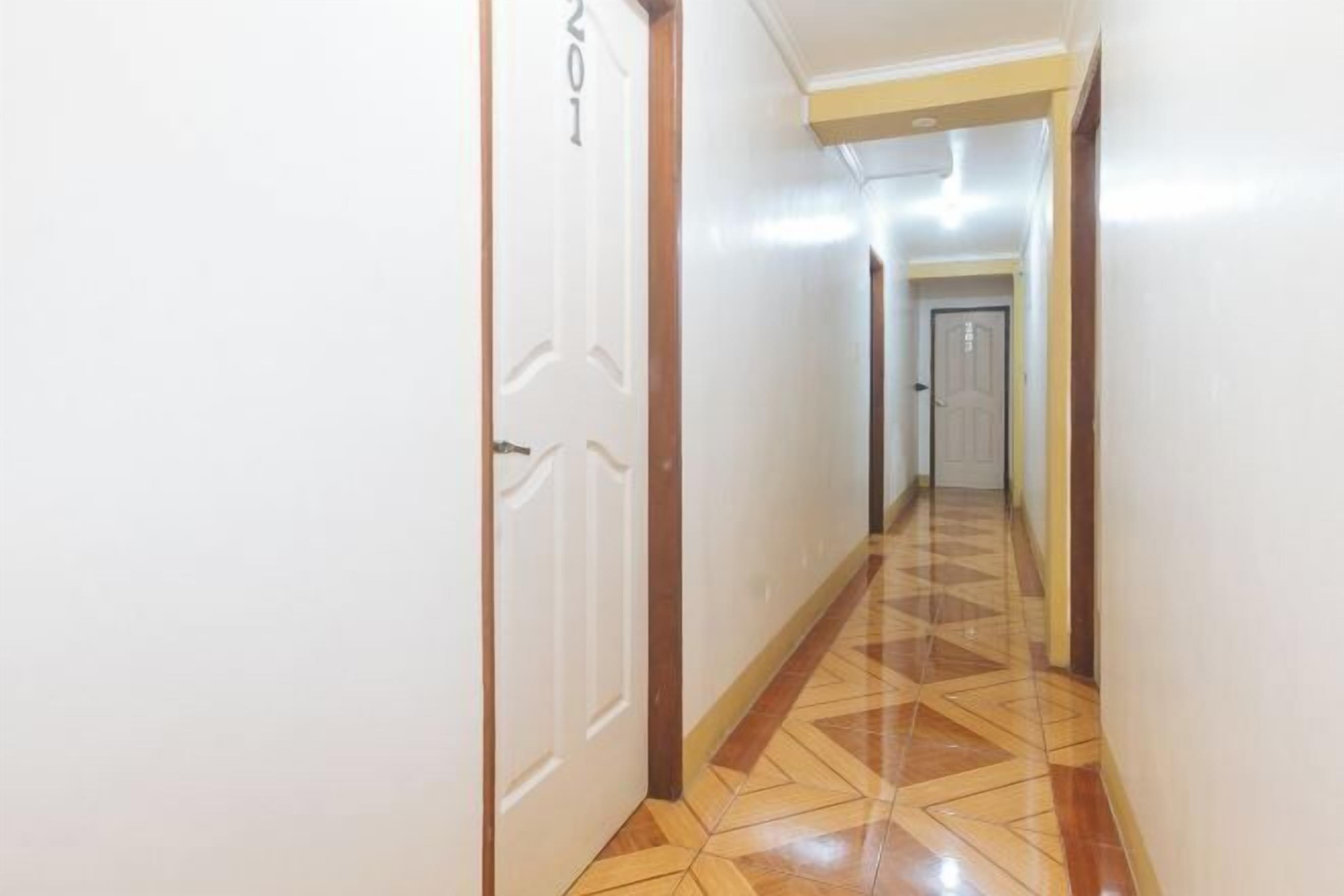 Un pasillo con piso estampado y una puerta con la etiqueta '201'.