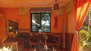 A room with a wooden sofa, a glass coffee table, and a potted plant. - RedDoorz @ Farm Side Hotel Laoag City (Laoag)