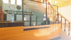A reception desk with a sign reading "FARM SIDE HOTEL" and a staircase with wooden railings. - RedDoorz @ Farm Side Hotel Laoag City (Laoag)