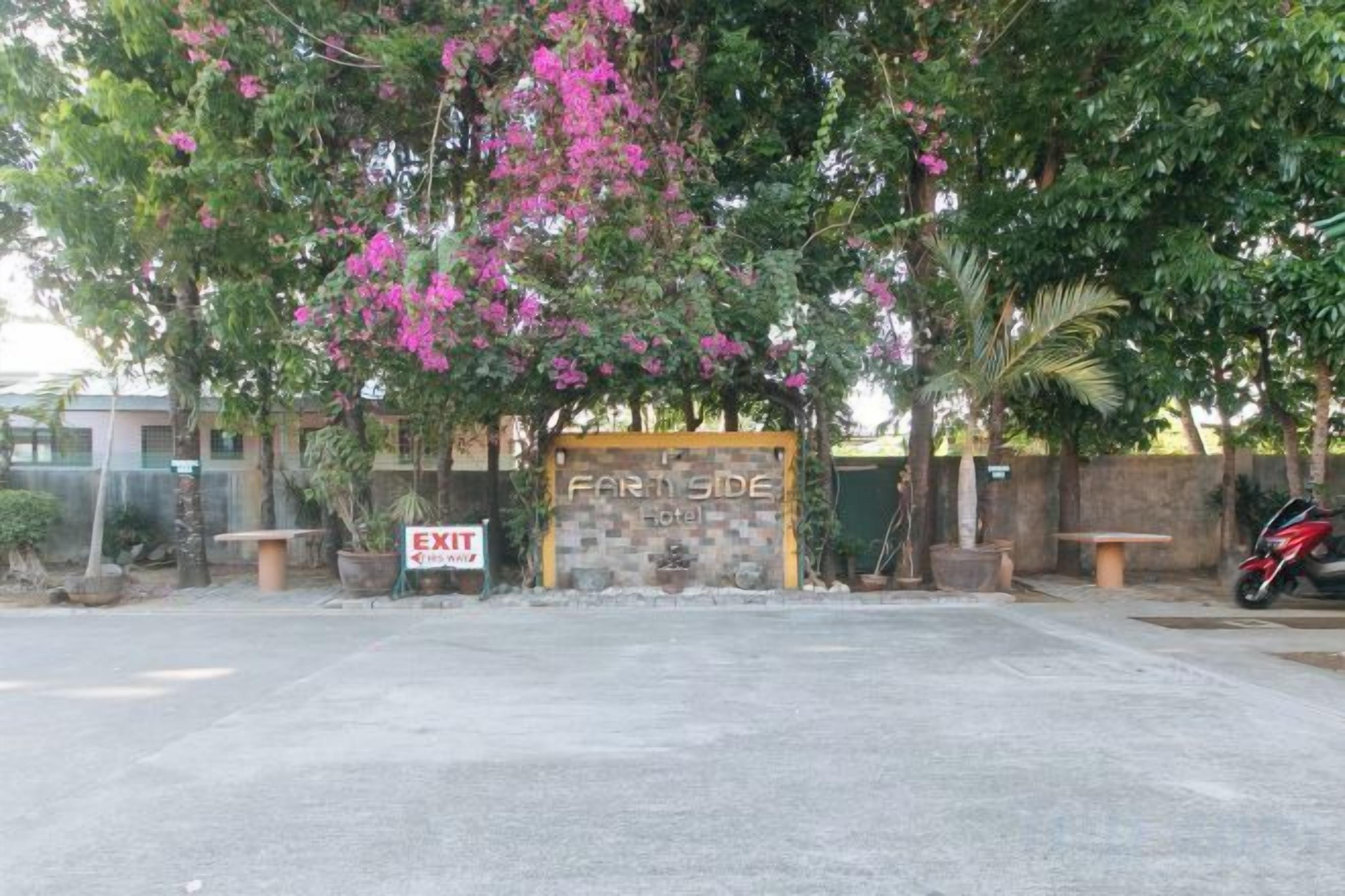 A gated entrance with a sign reading 'EXIT' and a 'FARM SIDE' sign. There are potted plants and a bench near the gate.
