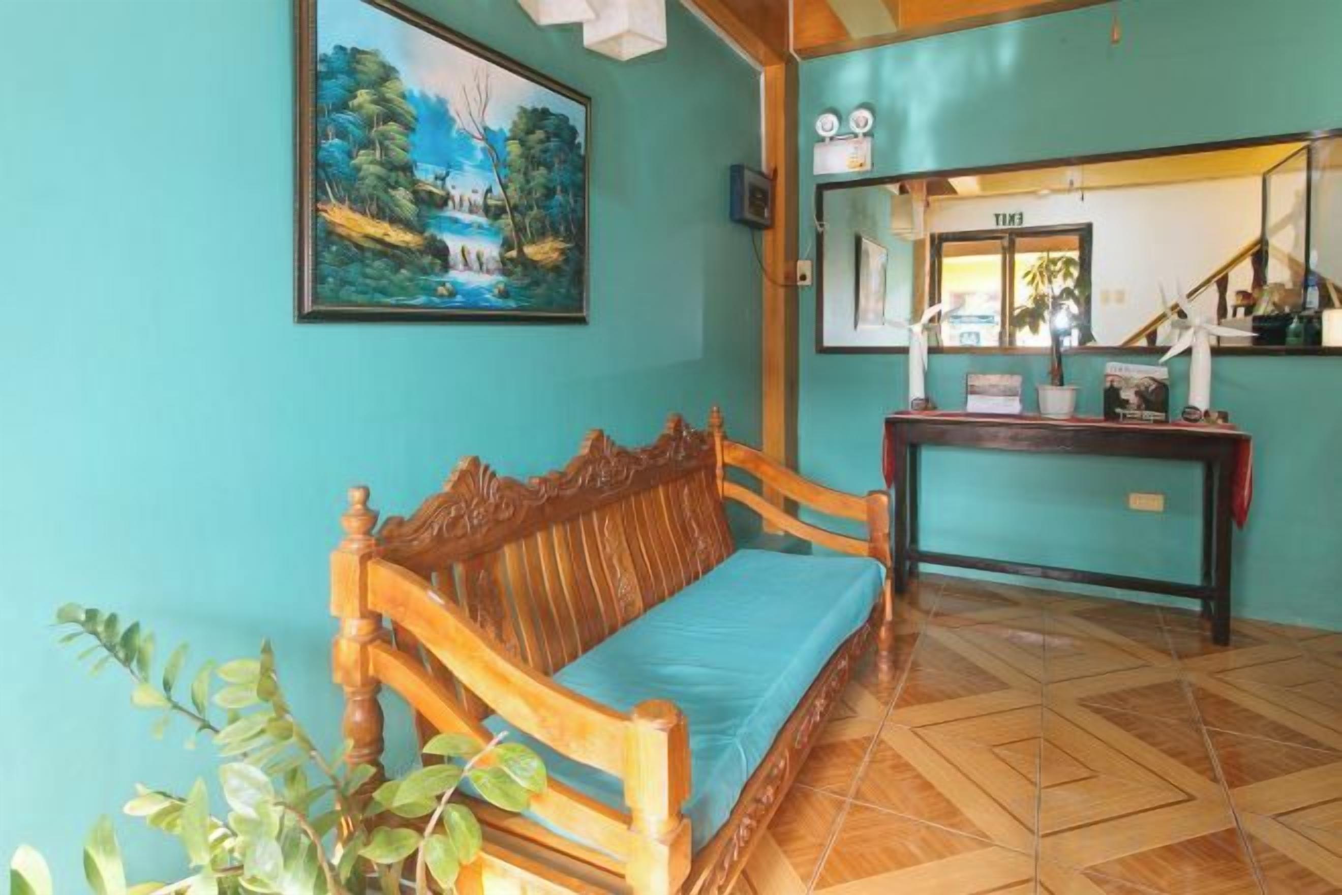Una habitación con un banco de madera, una mesita y un cuadro en la pared.