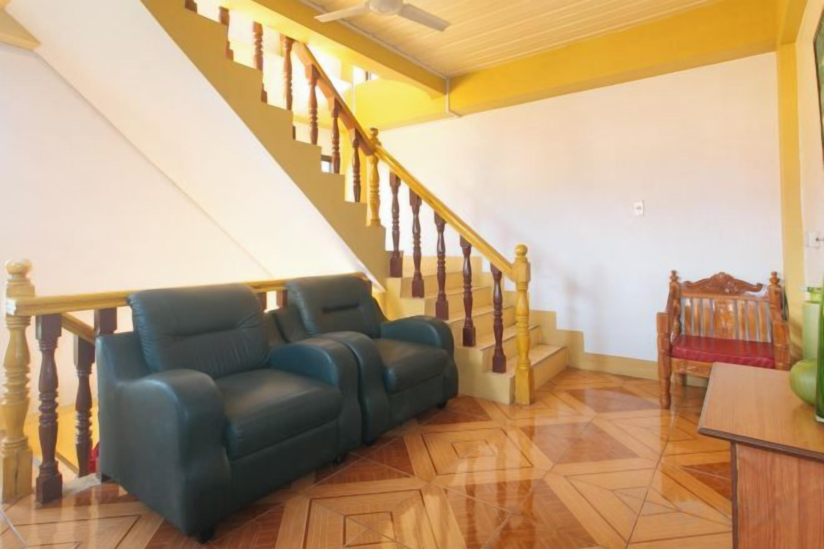 Una escalera con barandillas de madera y un sofá azul en una habitación con piso de baldosas.