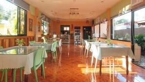 A restaurant with glass tables and chairs, a patterned floor, and large windows. - RedDoorz @ Farm Side Hotel Laoag City (Laoag)