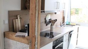 A modern kitchen with a wooden island, stainless steel appliances, and a large window providing natural light. - Mobys Hafenglück - Gemütliche 3-zimmer-wohnung für Groß und Klein (Neustadt in Holstein)