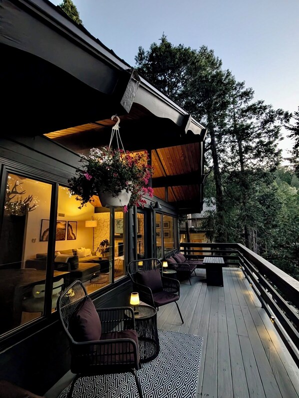 Eine moderne Terrassenanlage mit Sitzgelegenheiten, einem hängenden Blumentopf und Blick ins Innere.