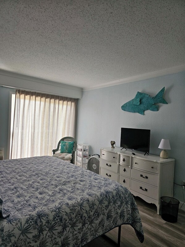 Un dormitorio con cama, cómoda, televisor y un adorno en la pared.