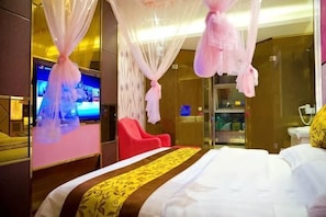 A hotel room with a bed, a TV, a red chair, and a glass shower area. - Aishang Boutique Hotel (Cixi)