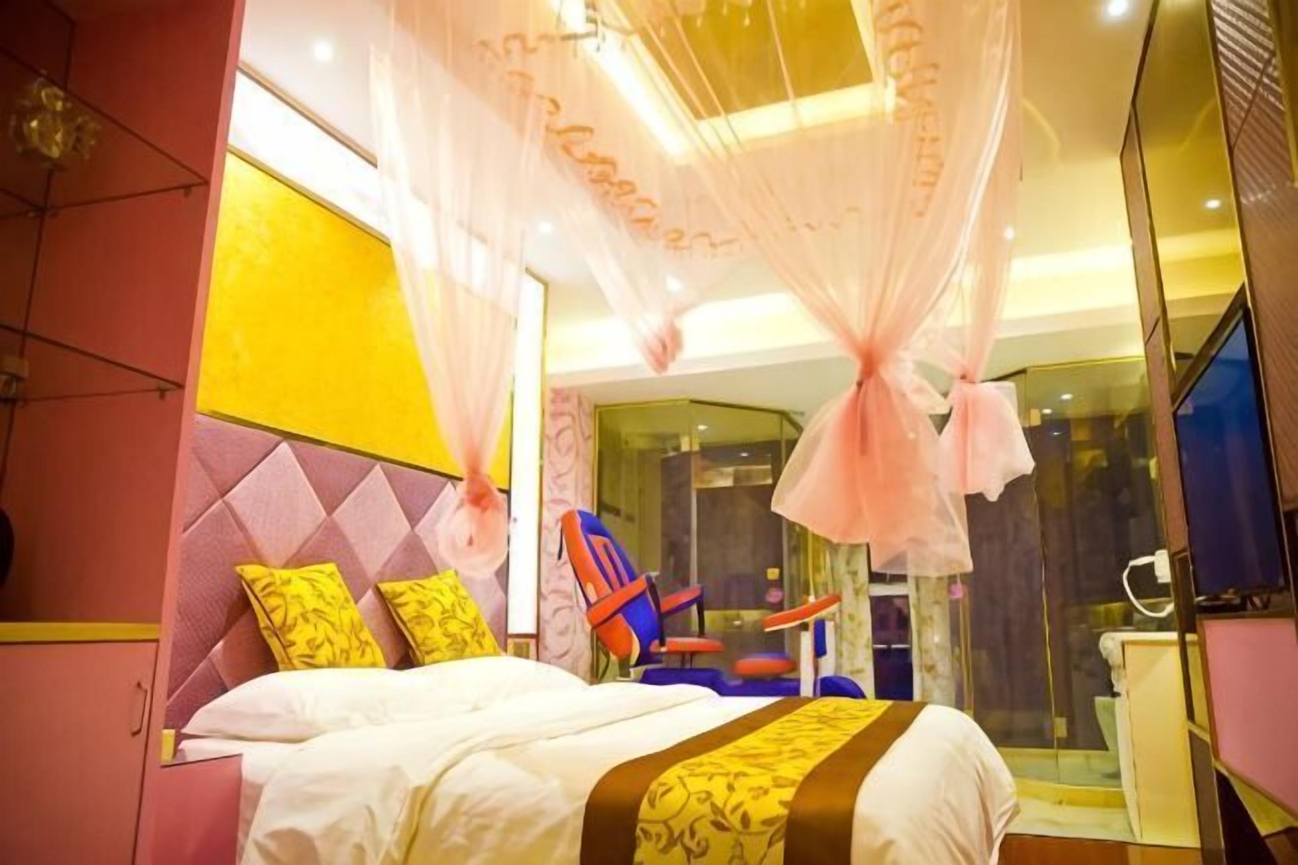 Un dormitorio con cama, una silla, ducha de vidrio y espejo.