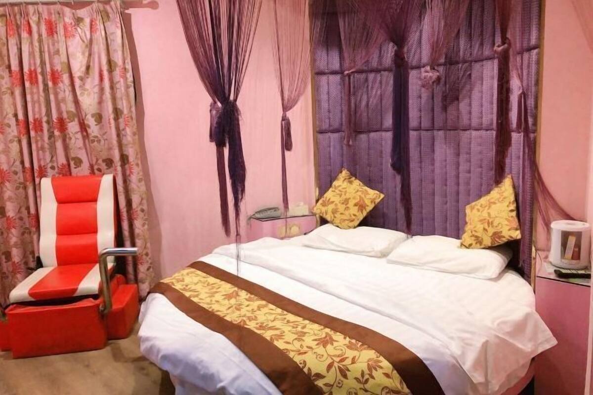 Une chambre d’hôtel avec un lit, une chaise rouge et blanche et un rideau.