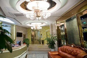 A hotel lobby with a reception desk, a leather sofa, a chandelier, and a staircase leading to the upper floors. - Aishang Boutique Hotel (Cixi)