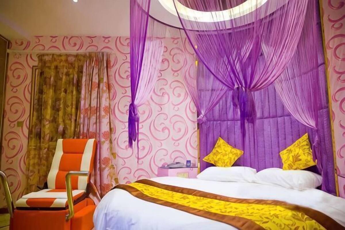 Une chambre d’hôtel avec un lit, une chaise et un rideau.