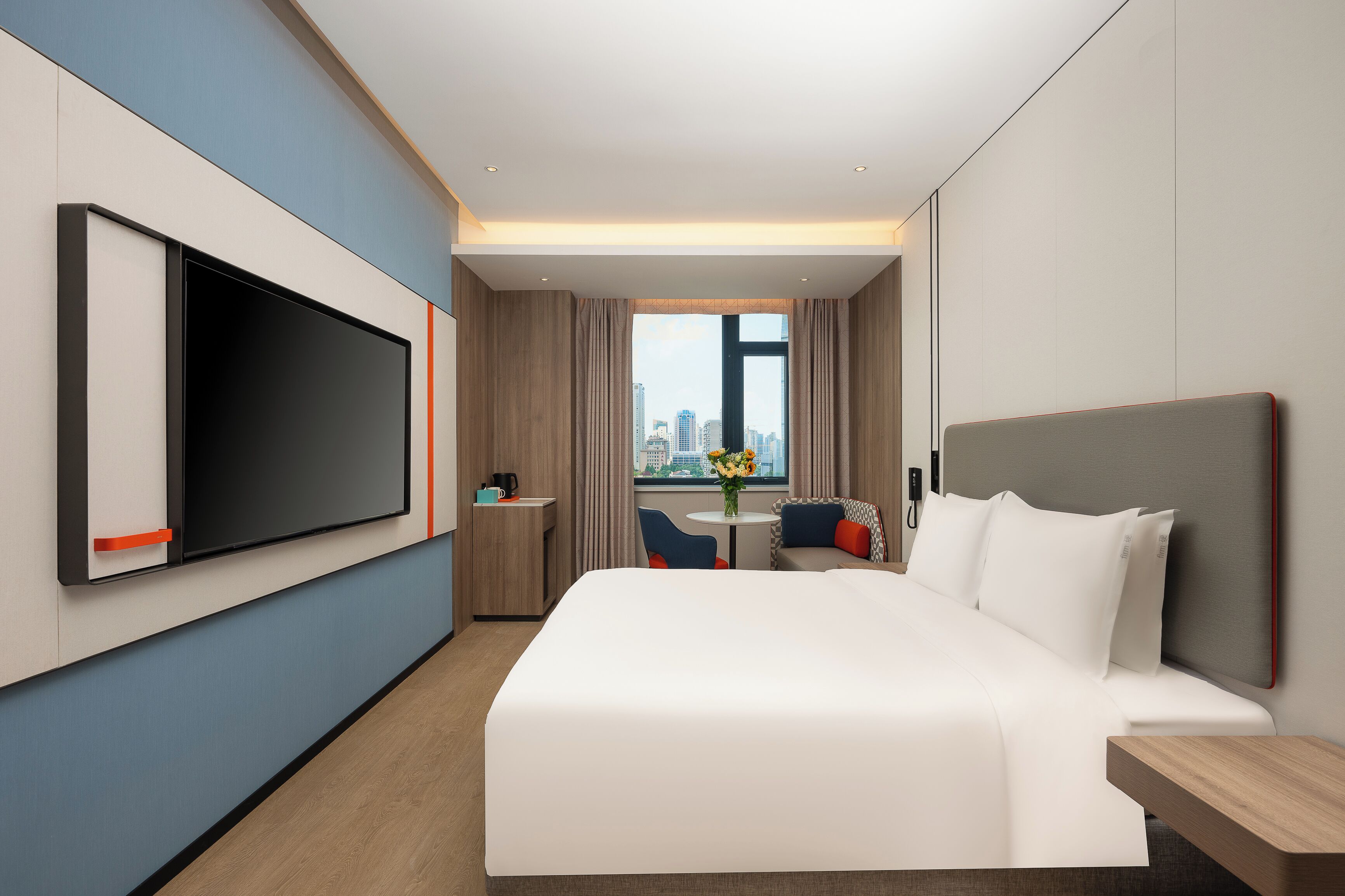 Une chambre d’hôtel moderne dotée d’un grand lit, d’une télévision, d’un bureau et offrant une vue sur la ville.